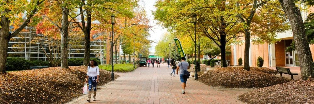 Photo of UNC Charlotte campus with fall leaves and people walking